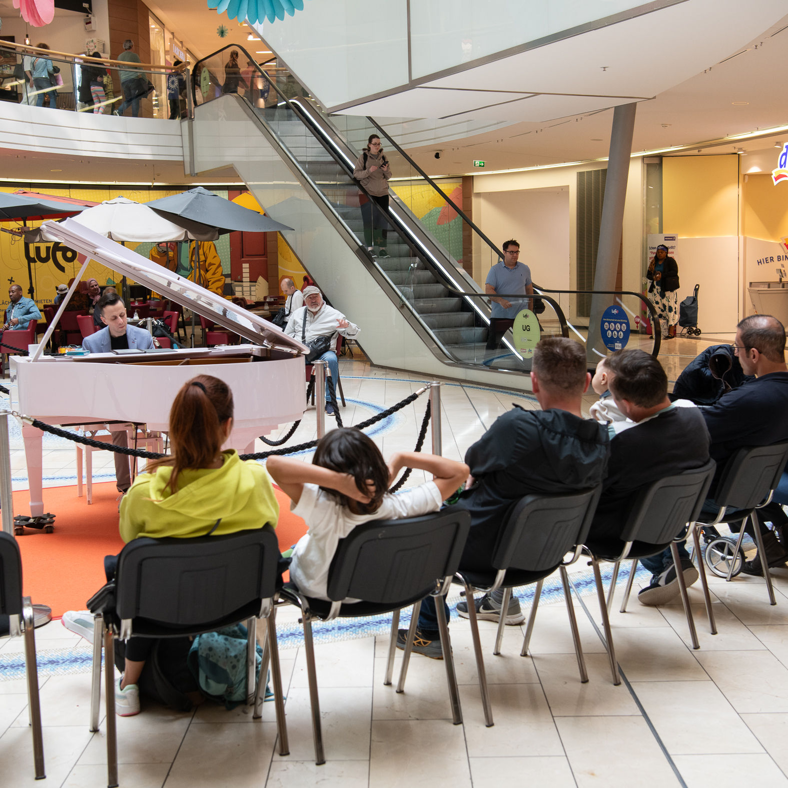 Mann spielt auf einem weißen Flügel im Einkaufszentrum