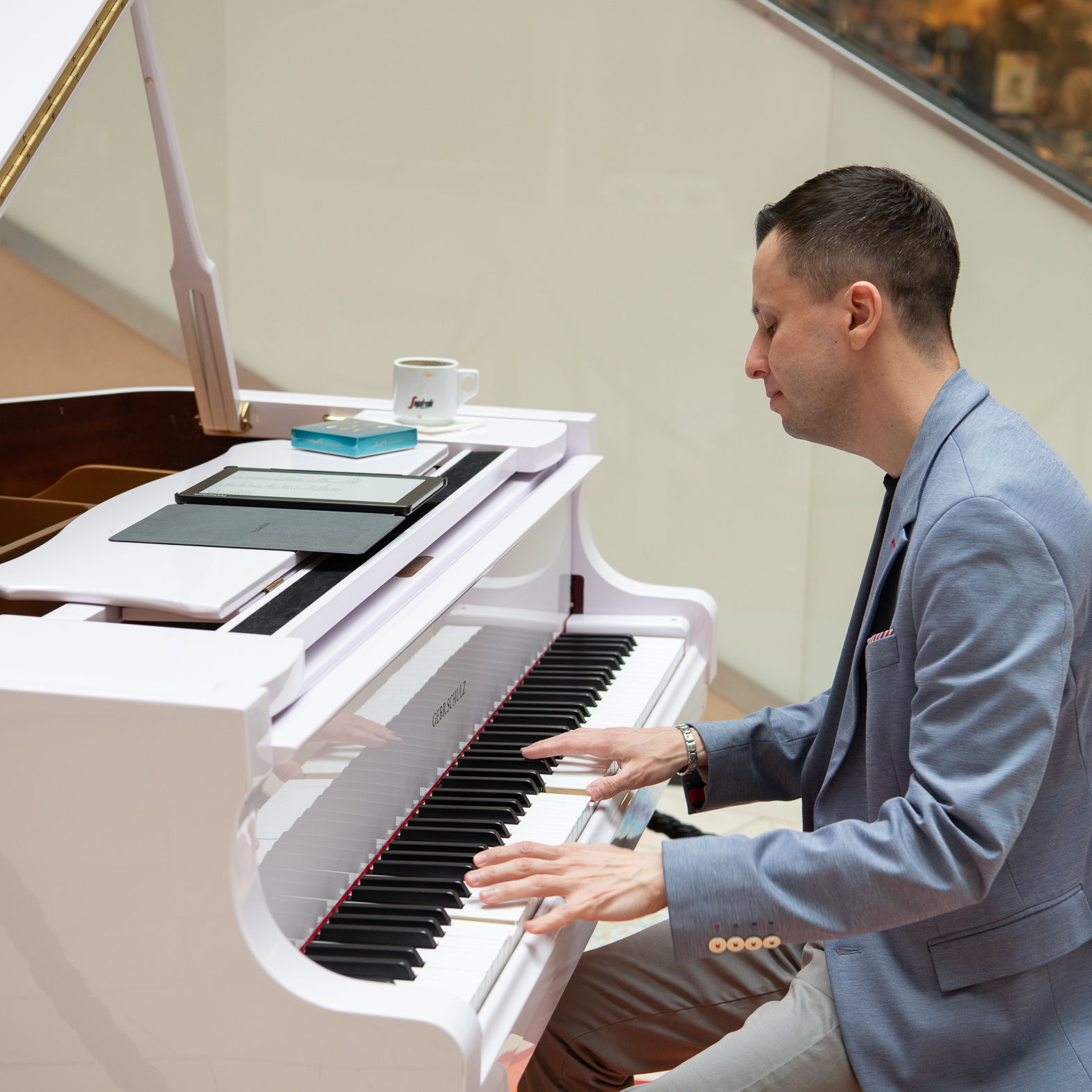 Mann spielt auf einem weißen Flügel im Einkaufszentrum